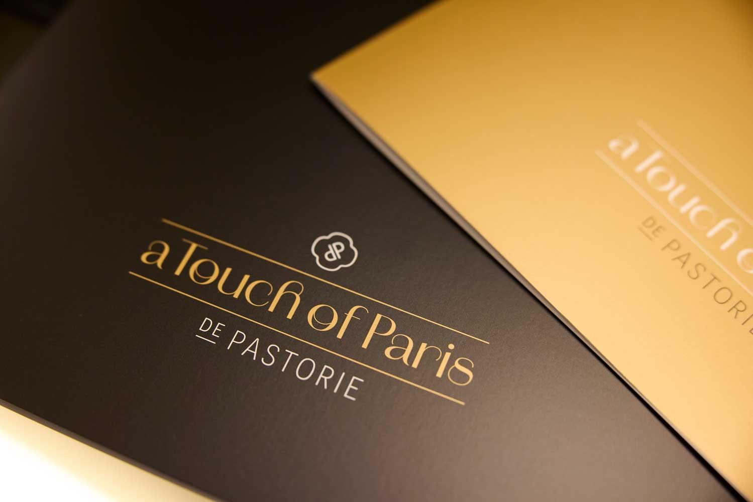 Detailopname van luxe drukwerk voor De Pastorie met goudfolie op een donkere achtergrond.