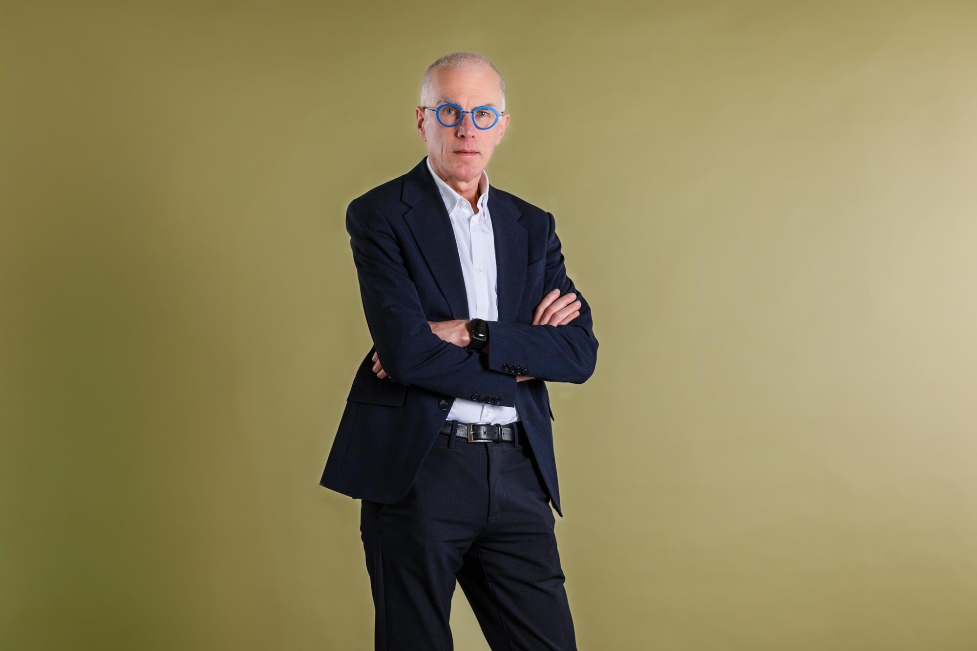 Brandle - personal branding met portretfotografie voor Jan Balliauw Zakelijk portret van Jan Balliauw, staand met gekruiste armen, blauwe bril en donker pak tegen een effen groene achtergrond.