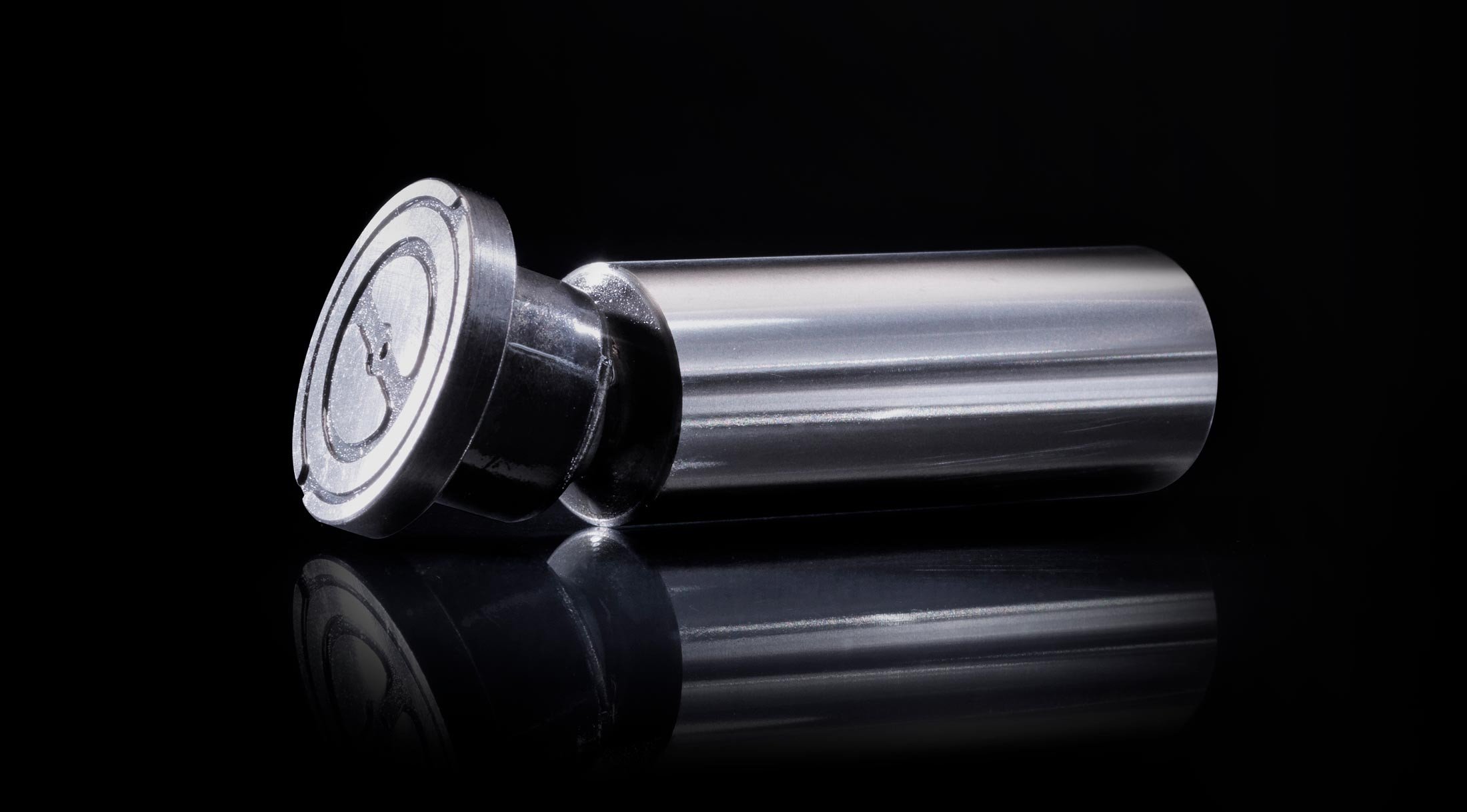 Glanzend metalen industrieel onderdeel gefotografeerd tegen een zwarte achtergrond.