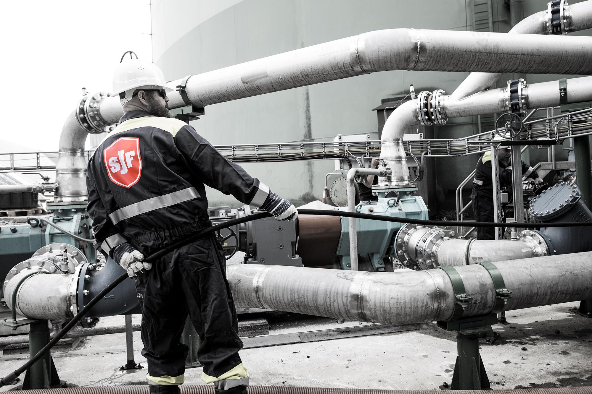 Brandle - Bedrijfsfotografie voor Smet Jet Medewerker van SJF in beschermende werkkleding werkt aan industriële leidingen en installaties in een technische omgeving.